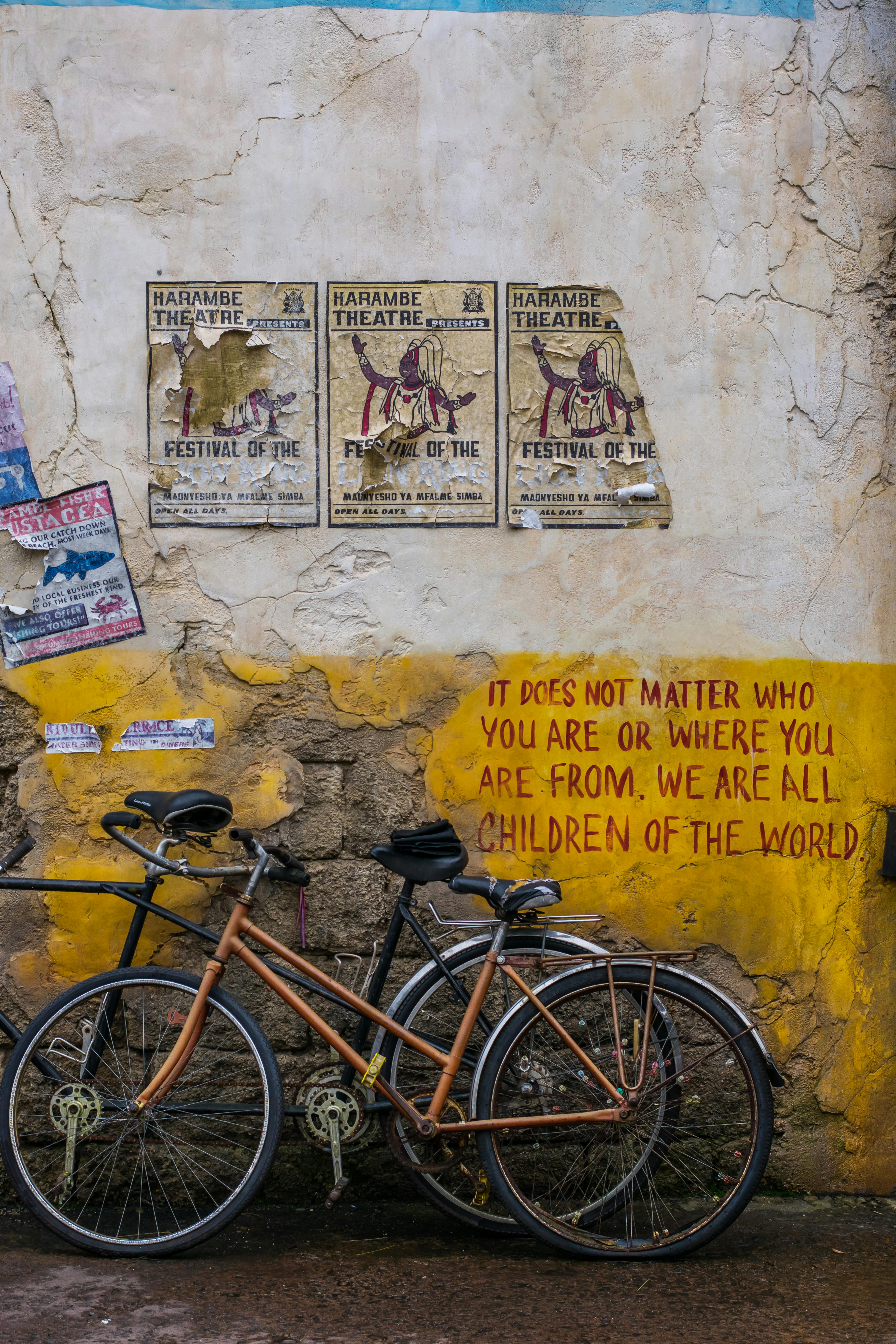 Free Two bicycles against a wall with festival posters and street art in vibrant city scene. Stock Photo