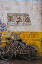 Two Bikes Standing at Dingy Wall with Old Posters and Inscription
