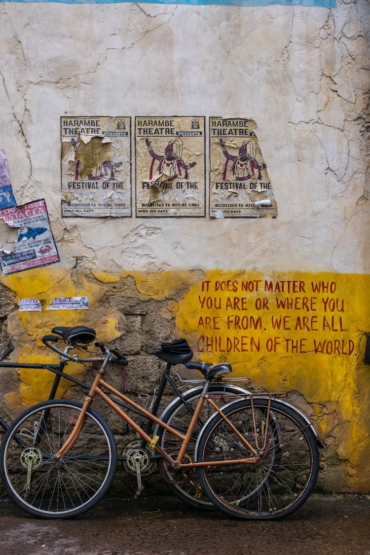 Two Bikes Standing At Dingy Wall With Old Posters And Inscription