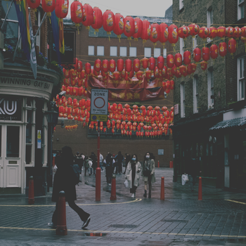 A vibrant street scene in London's Chinatown with red lanterns and masked pedestrians, capturing cultural atmosphere.（イメージ）
