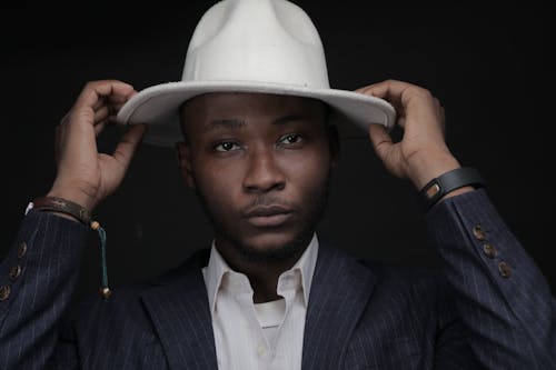 A Man Wearing a Suit while Holding His White Hat