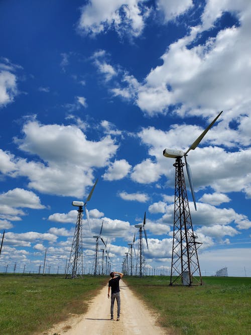 Photo of a Man Standing Near Wind Turbines