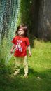 Boy in Red Crew Neck T-shirt and Green Pants Standing on Green Grass Field during