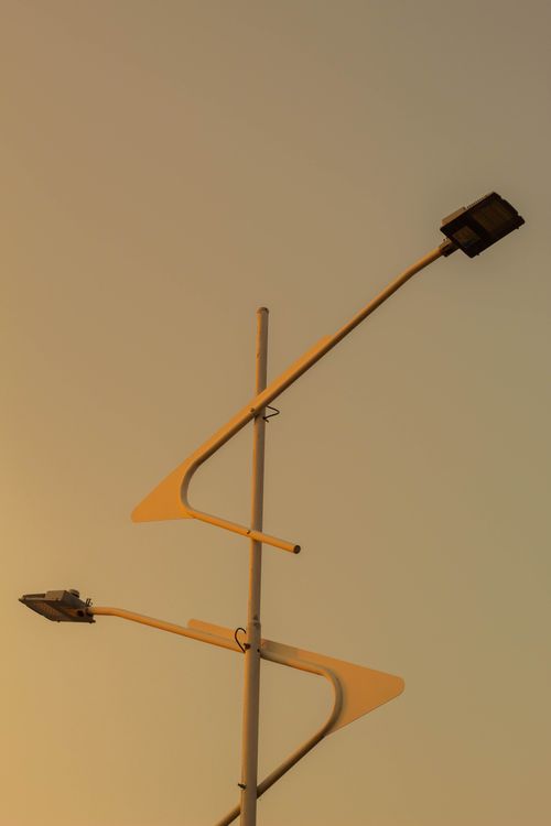 Free Silhouetted modern solar street lights against a sunset sky, highlighting contemporary urban design. Stock Photo