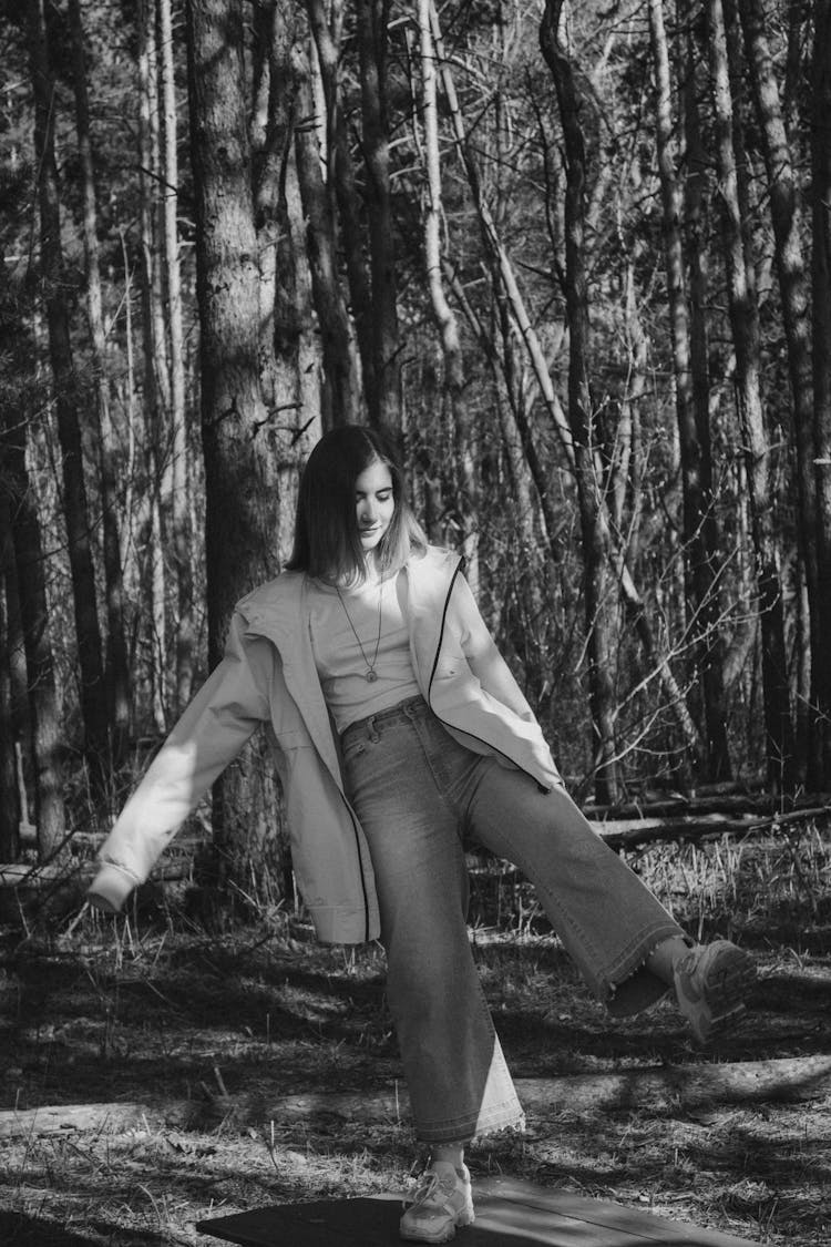 Woman In Oversized Coat And Bell Bottom Jeans In Forest