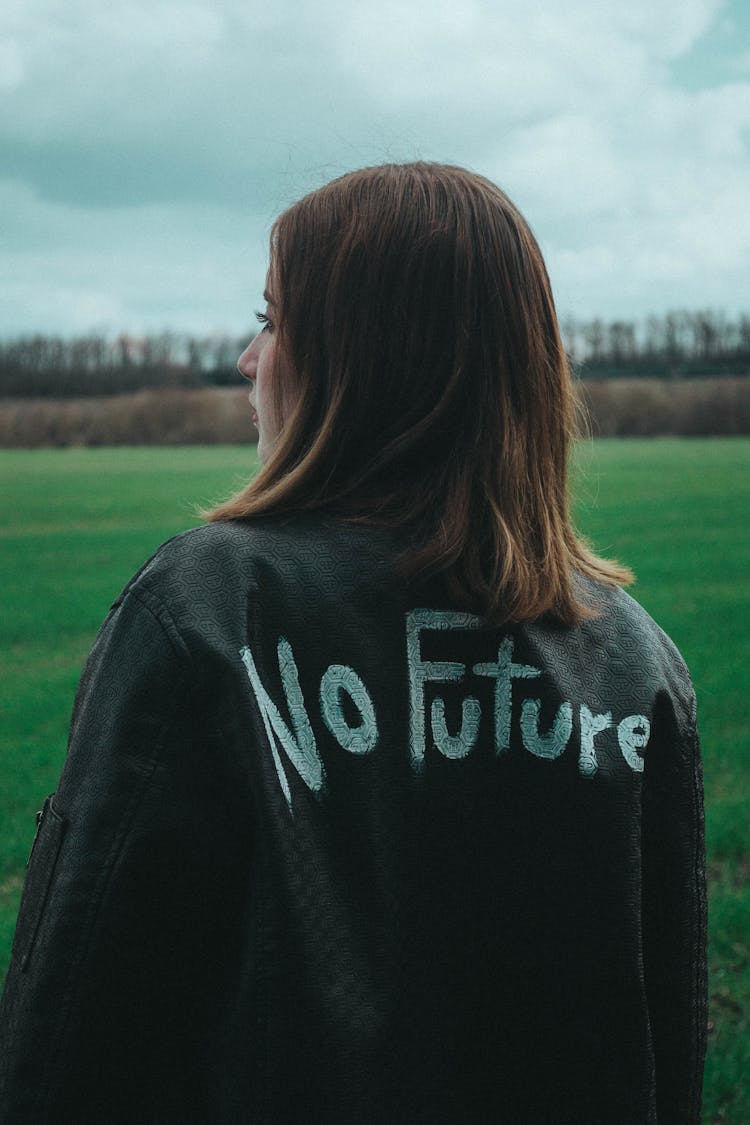 Woman In Black Coat With Statement Painted On Back