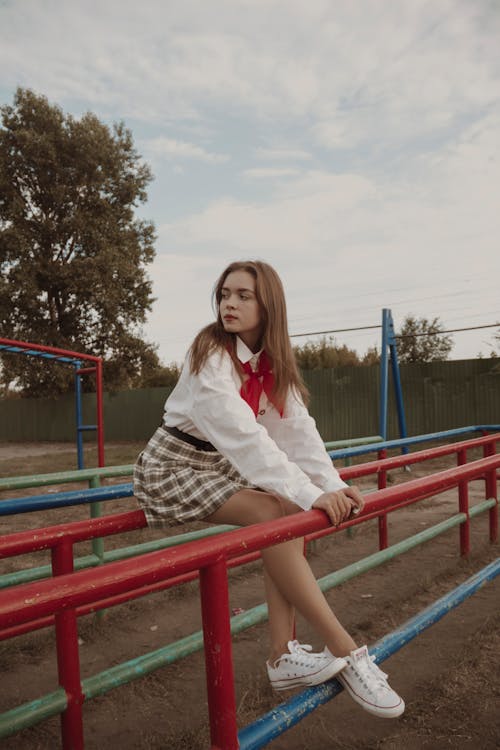 Portrait of Brown Hair Girl in White Shirt Sitting on Metal Railing