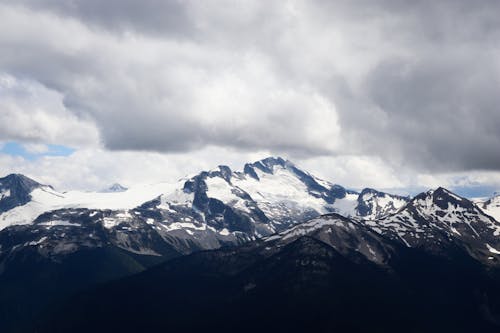 Rock Mountains Covered with Snow under the Gray Clouds 