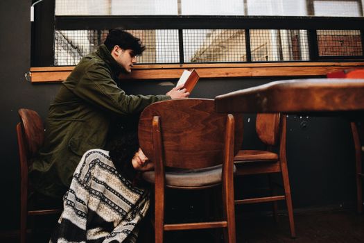 Man Sitting at Table and Unrecognized Person Sitting on Floor at Cafeteria 