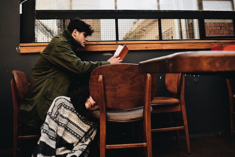 Man Sitting At Table And Unrecognized Person Sitting On Floor At Cafeteria 