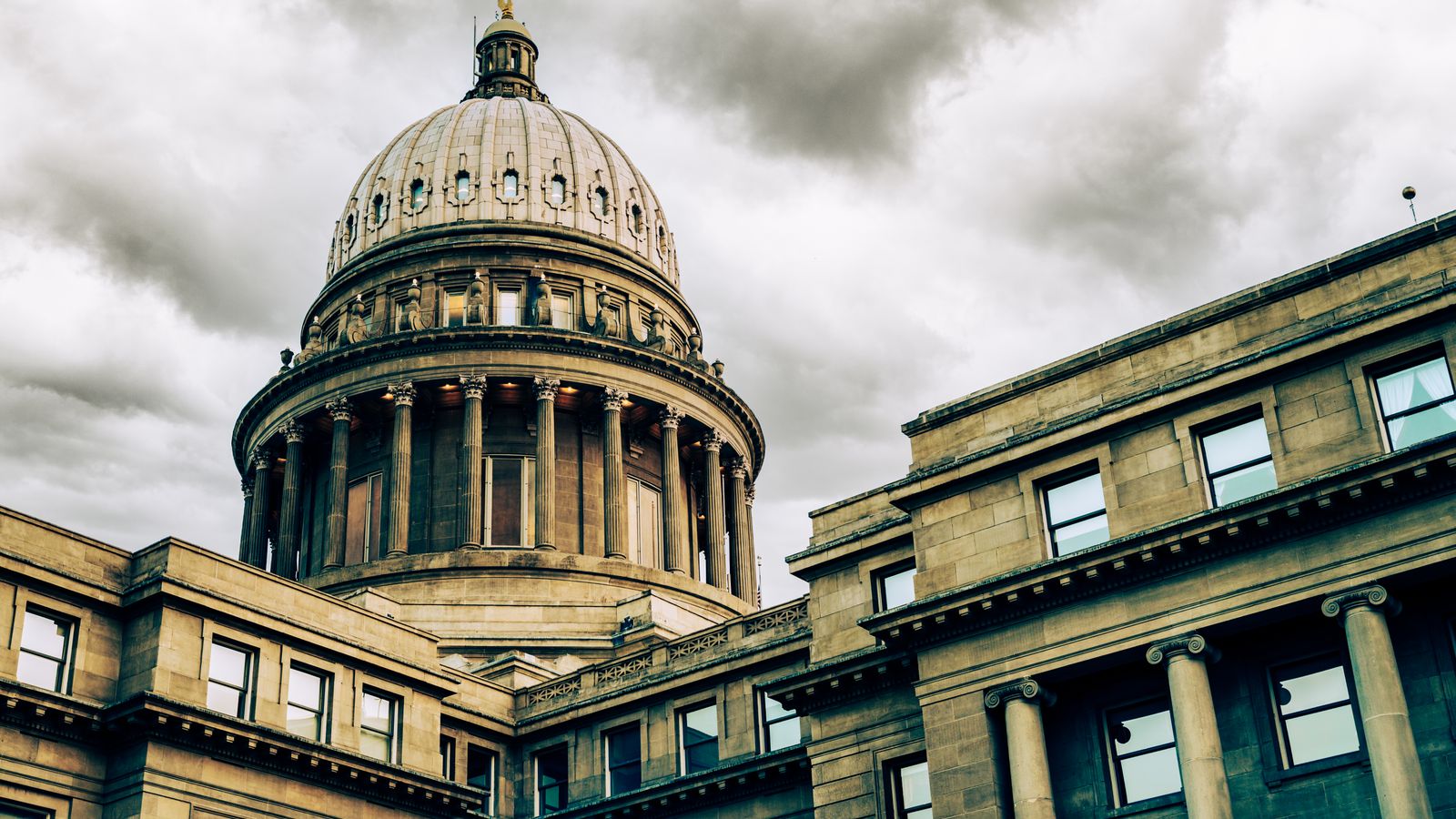 Stunning view of a classic capitol building with a prominent dome set against a dramatic, cloudy sky.