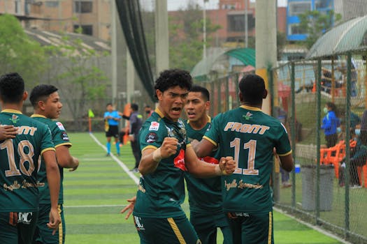 Group of young football players celebrating a successful play during a match.