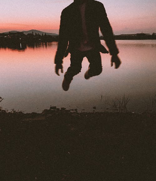 Man Jumping on Lakeshore