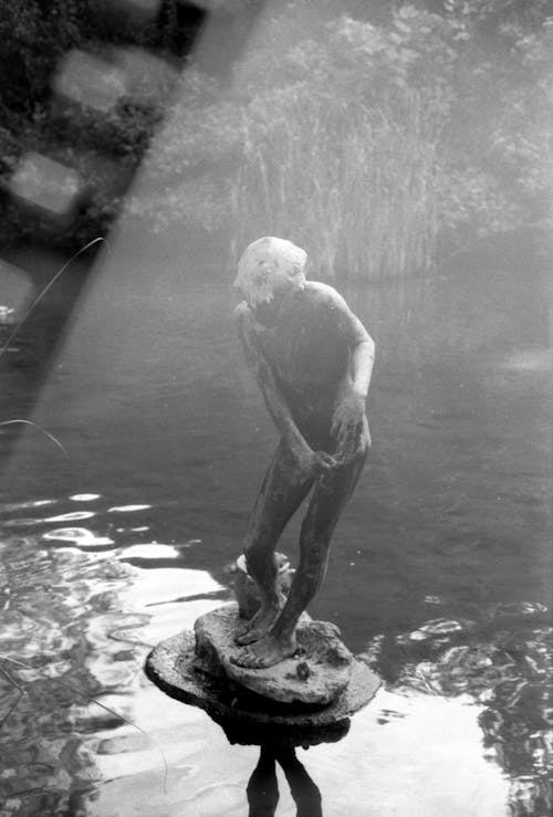 Black and White Picture of Statue of Man on Pond