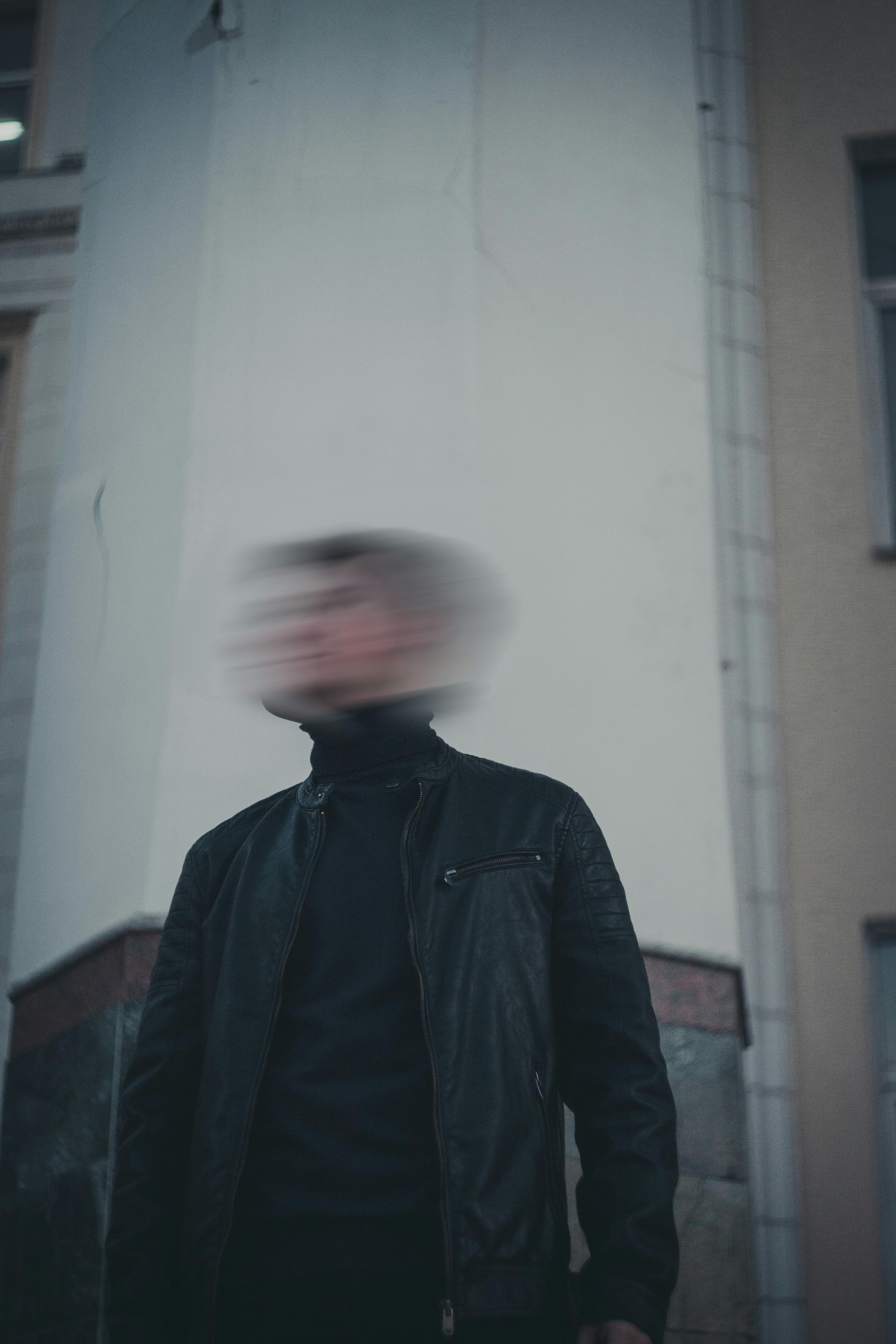 Artistic blurred motion portrait of a man standing in an urban environment, capturing a modern and moody vibe.