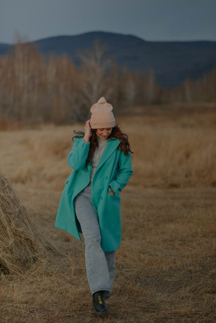 Woman In Tea, Coat Walking Past Hay