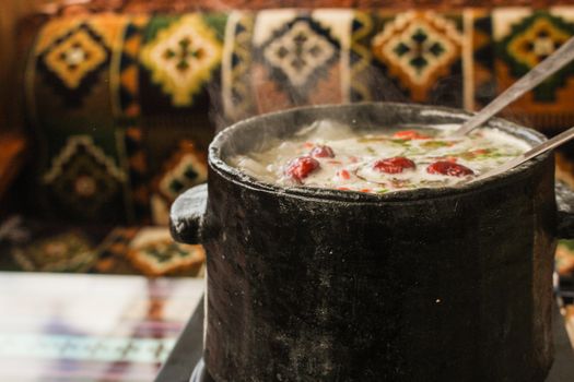 A steaming hot soup served in a rustic clay pot, exuding warmth and flavor.