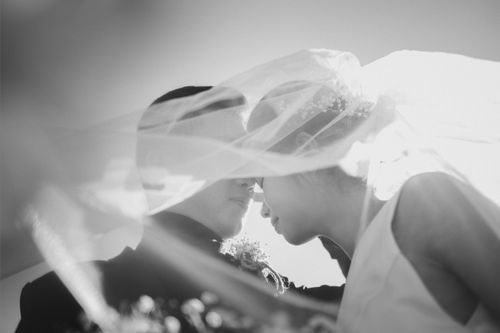 Free Newlywed couple in a tender embrace under bridal veil. Stock Photo