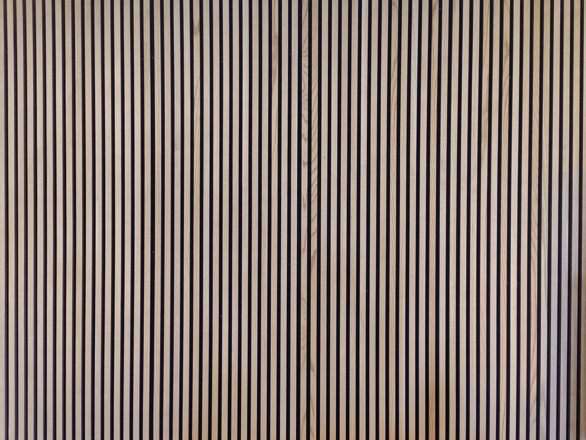 Fluted wood panel wall behind a TV with a low console in a neutral living room