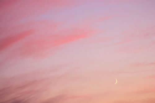 Free A tranquil crescent moon setting against a pink and purple sky, evoking calm and peace. Stock Photo