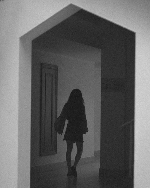 Free Artistic black and white silhouette of a woman walking in a hallway, creating a moody ambiance. Stock Photo