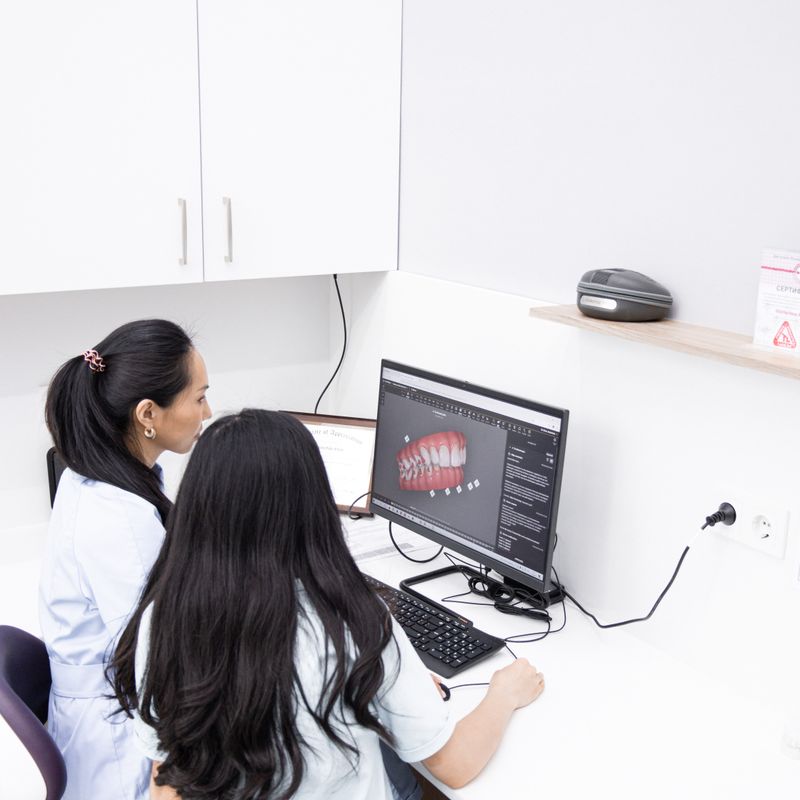 Dental clinicians reviewing a three-dimensional tooth model on a computer