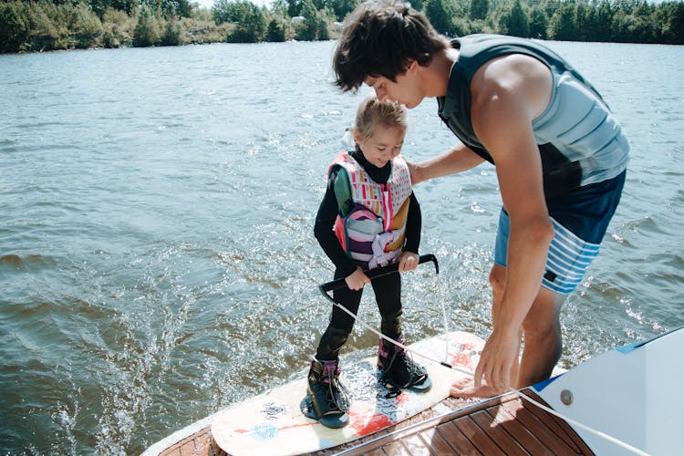 Young Girl Preparing To Wake Boarding With Her Father