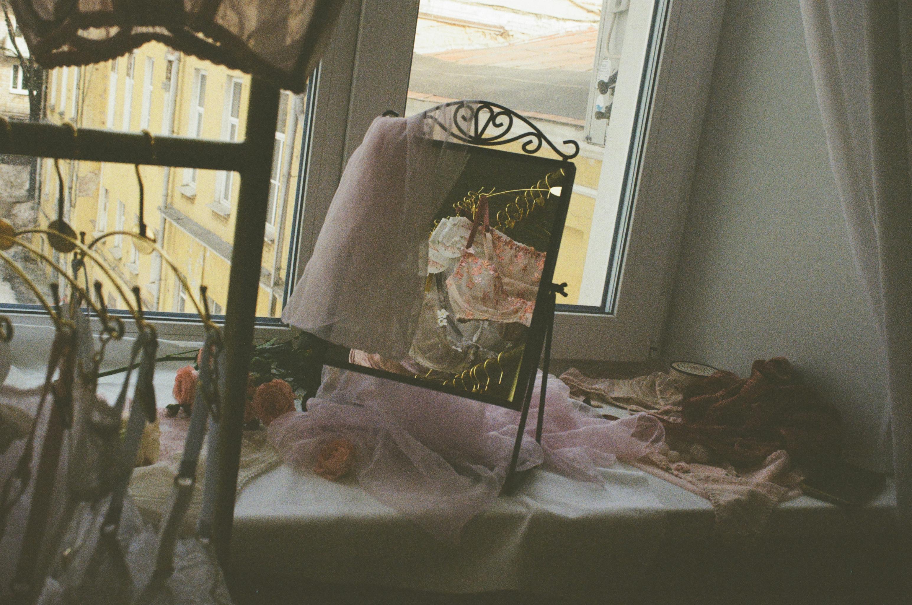 A charming corner with a mirror reflecting delicate fabrics and soft pastel tones inside an inviting room.