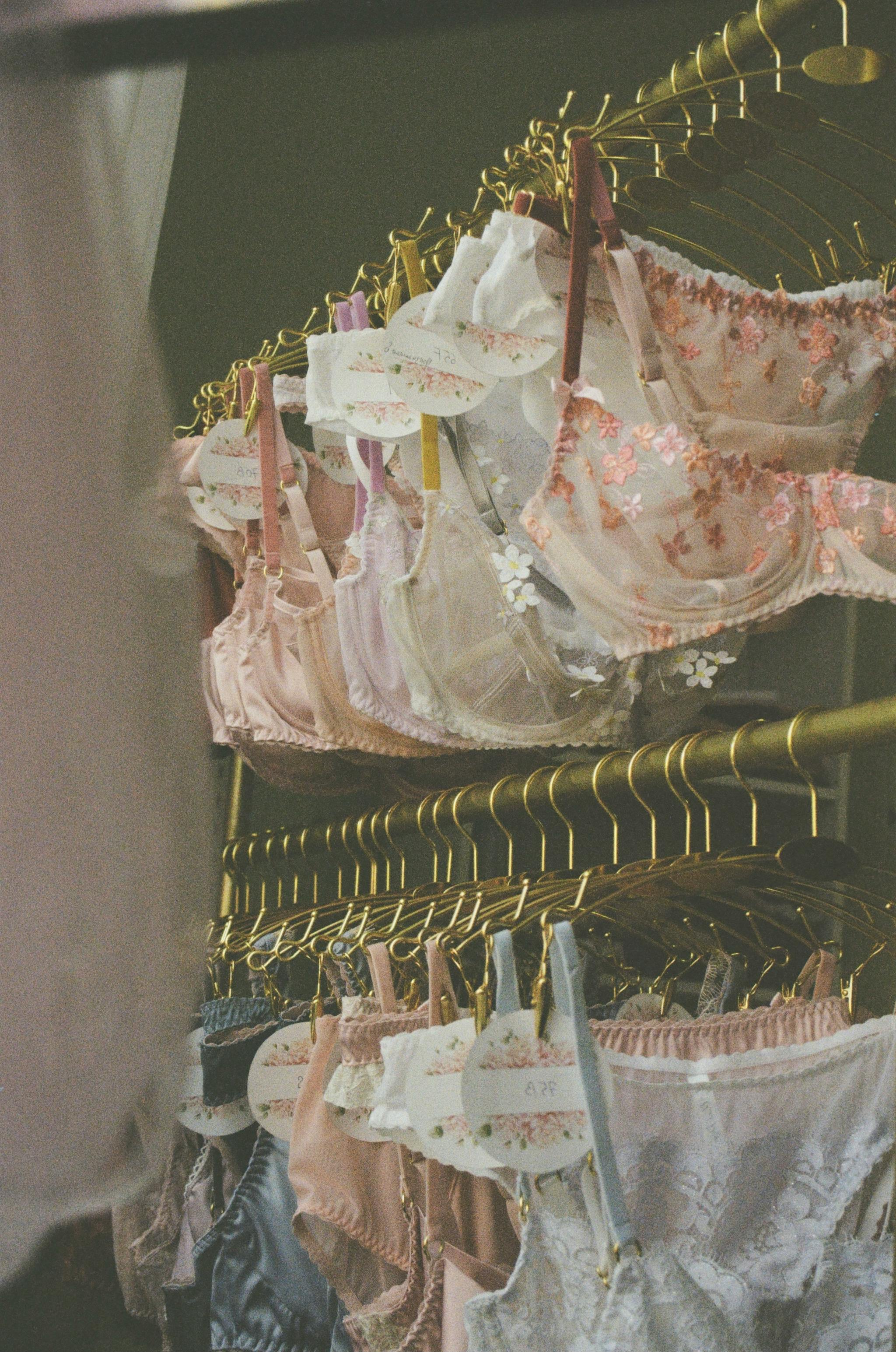 Close-up of various bras on hangers, showcasing elegant lingerie in pastel colors.