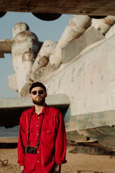 Stylish tourist standing in front of a large historic aircraft outdoors.