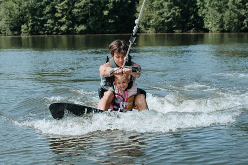 Free A father and daughter enjoying a thrilling wakesurfing experience on a sunny day. Stock Photo