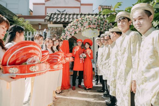 Traditional Vietnamese wedding with bride and groom in vibrant attire surrounded by friends.