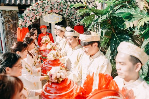 Colorful traditional Asian wedding ceremony featuring guests exchanging gifts outdoors.
