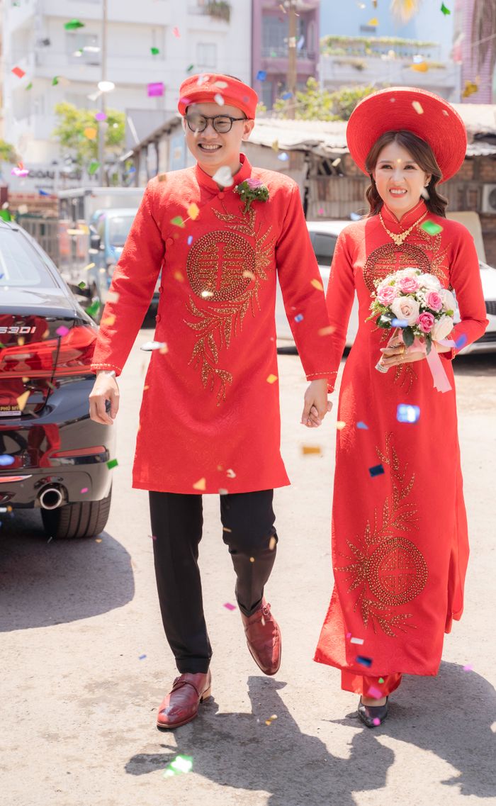 Cô dâu chú rể áo dài đỏ đi giữa confetti sau lễ cưới