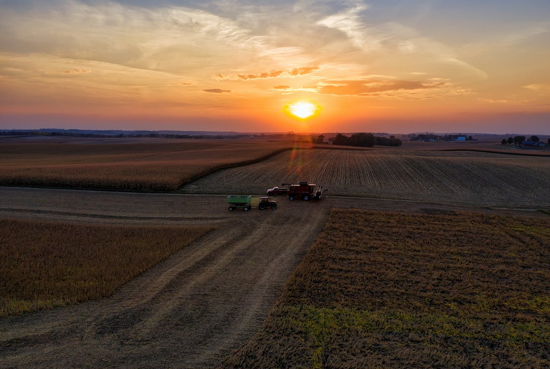 Aerial Photography of Tractors on Agricultural Land During Golden Hour