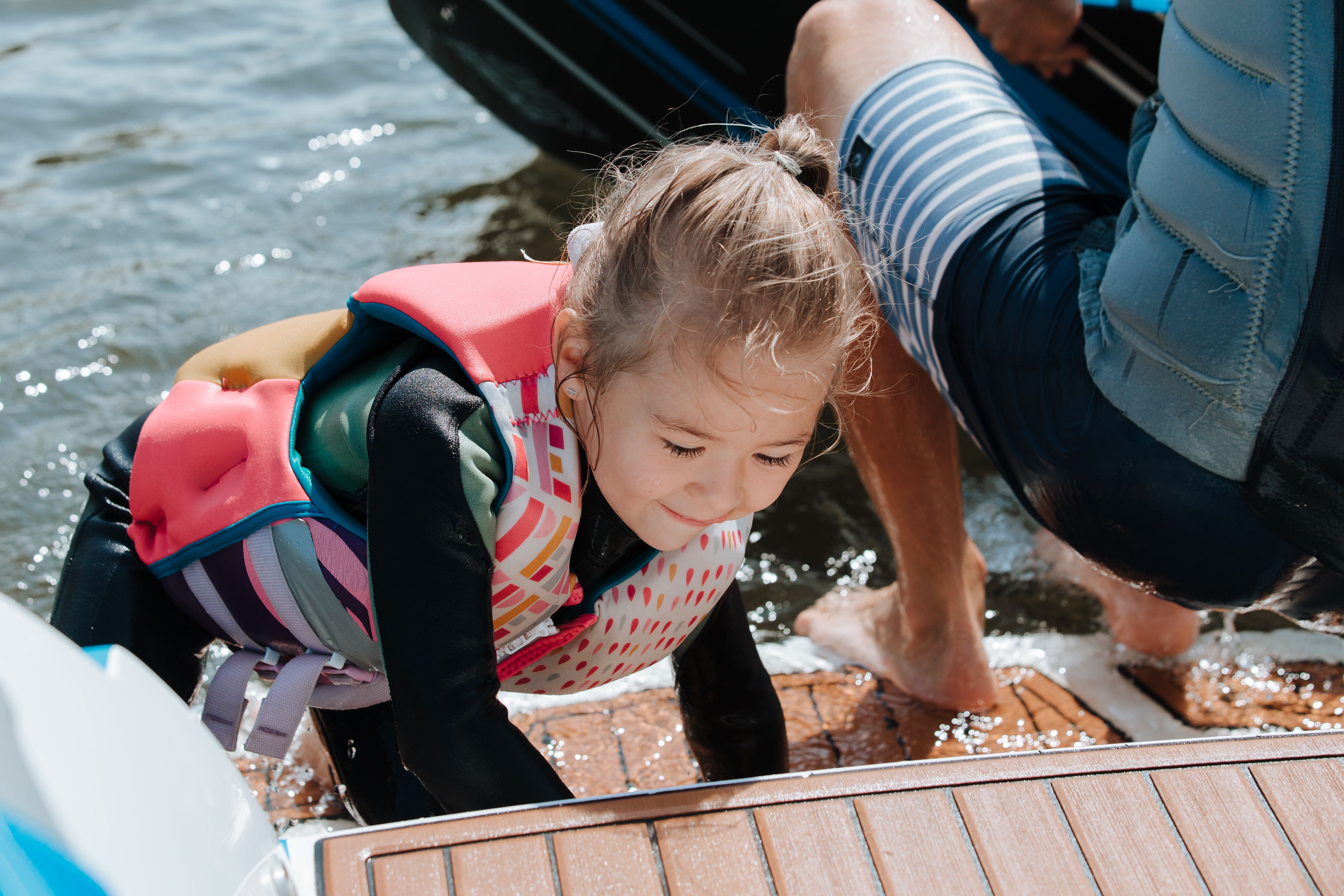 A young girl in a life vest enjoying a boating adventure with an adult on Wallis Lake