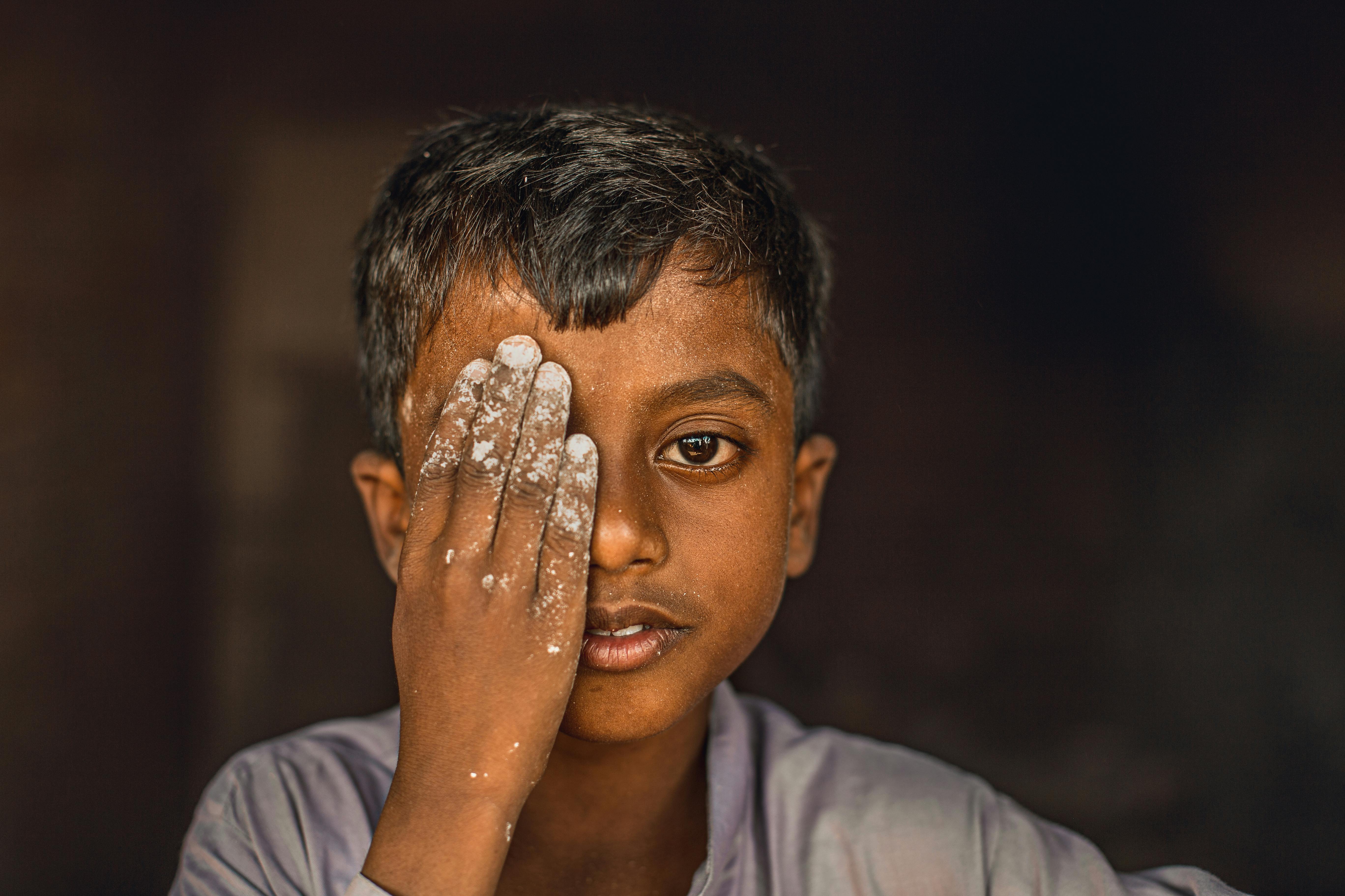 portrait of a little boy covering one eye with his hand