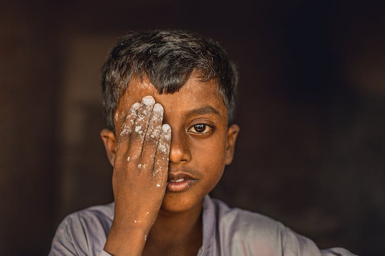 Portrait Of A Little Boy Covering One Eye With His Hand