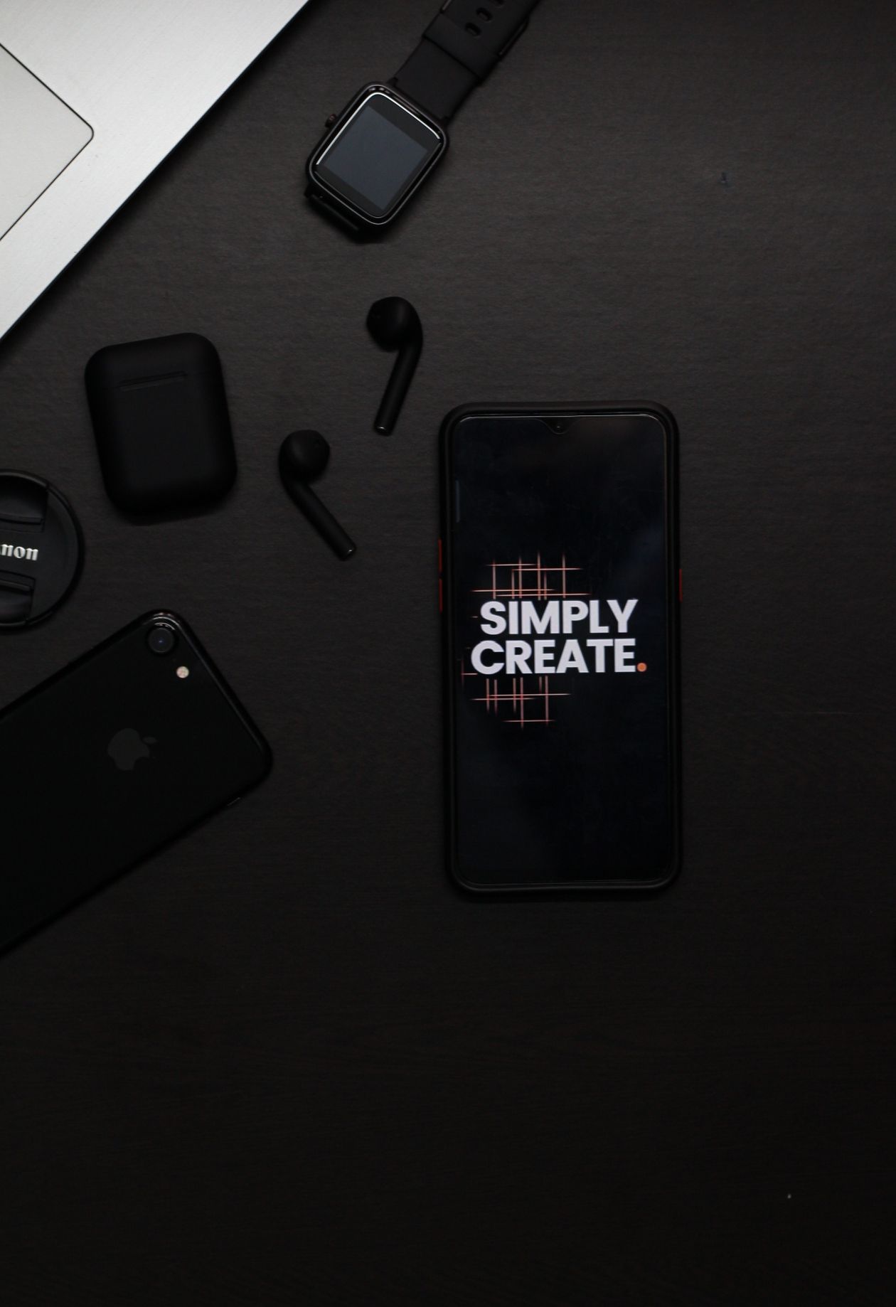 A real photograph of a smartphone, smartwatch and wireless earbuds on a dark surface; illustrative devices