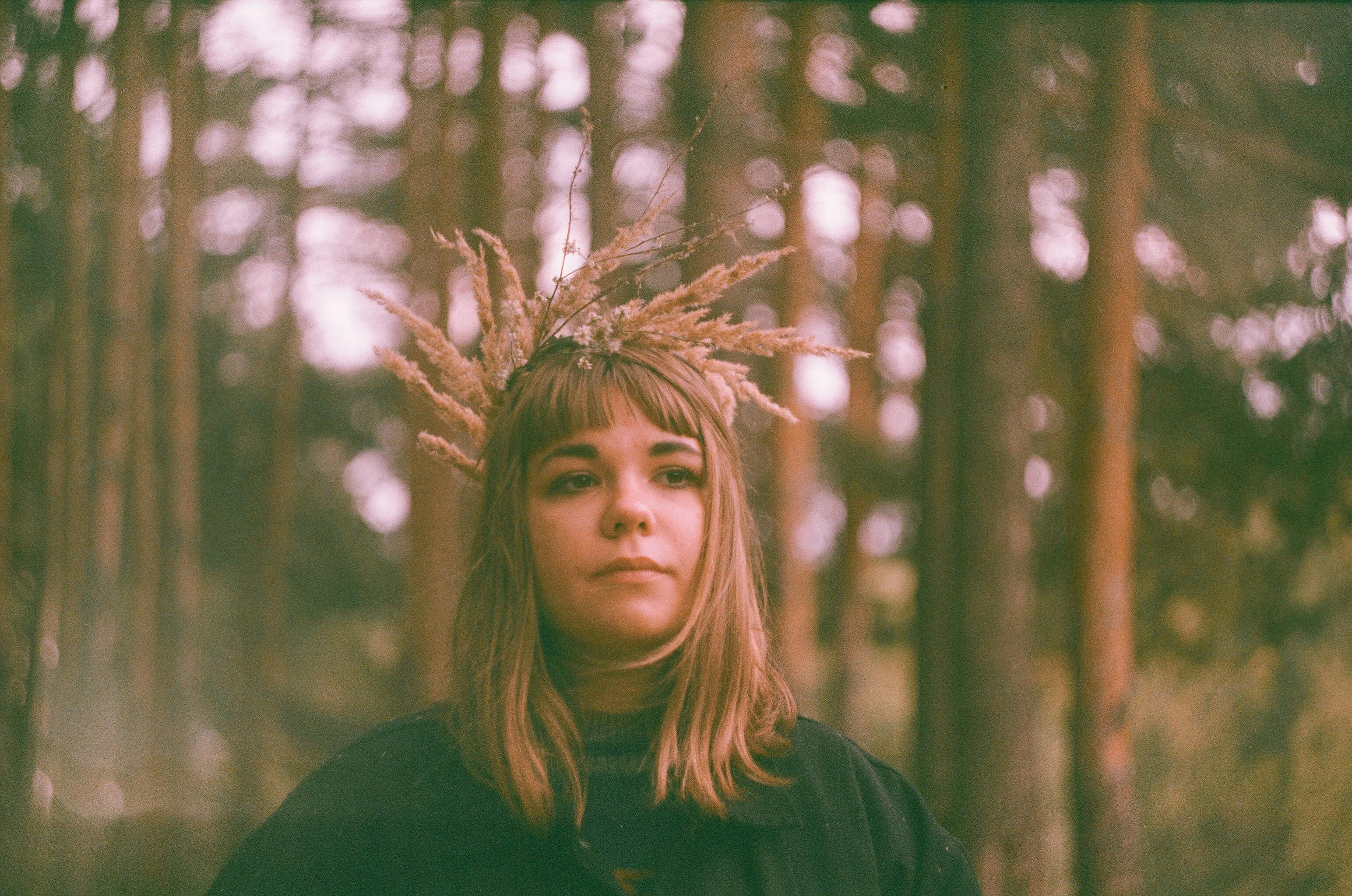 A dreamy portrait of a woman with a wheat crown in an autumn forest, evoking a mystical vibe.