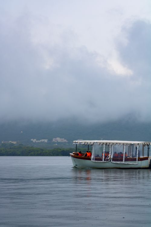 Free Serene boat ride on misty Lake Pichola in Udaipur, capturing a tranquil and scenic view. Stock Photo