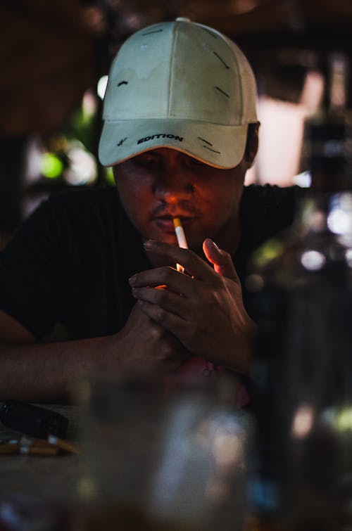 Man with a Cap Lighting a Cigarette 