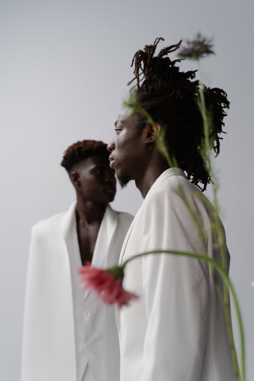 Free Elegant fashion portrait of two men in white suits adorned with flowers. Stock Photo