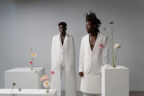 Men Wearing White Suits Standing Beside the Boxes with Flowers 