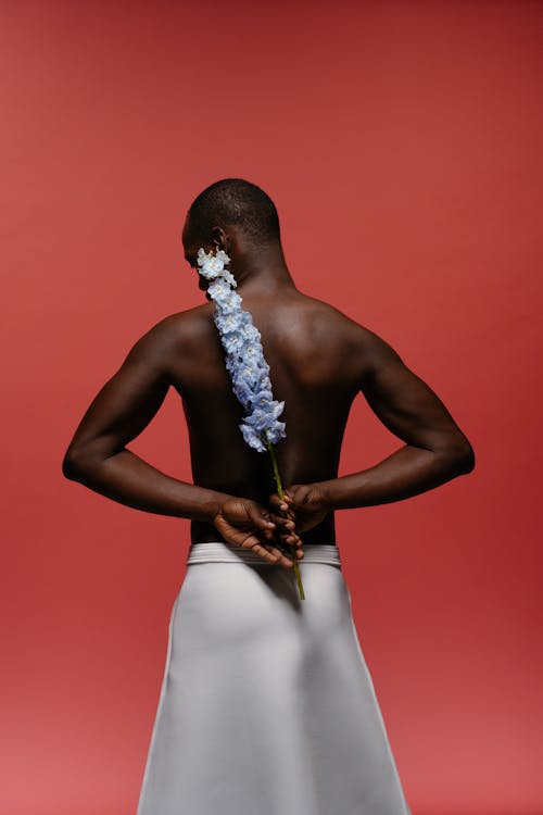 Topless Man Wearing White Skirt Holding Flower