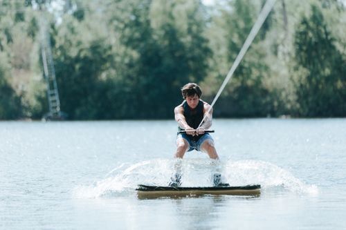 Free Man wakeboarding on a lake, showcasing adventure and sport in a scenic outdoor setting. Stock Photo