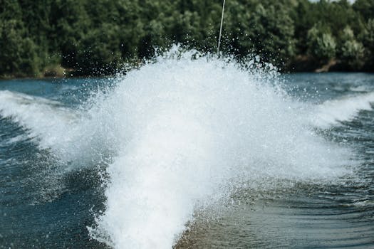 Capturing the powerful splash of water on a serene lake, surrounded by lush trees.