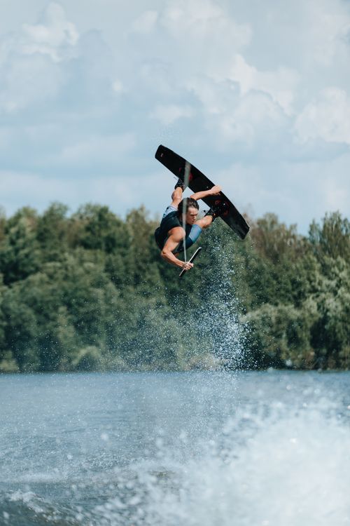 Free A skilled athlete performs an airborne wakeboarding trick during daylight on a lake. Stock Photo