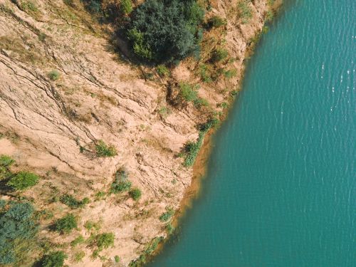 Free A stunning aerial shot depicting a rugged cliffside meeting a serene body of water. Stock Photo