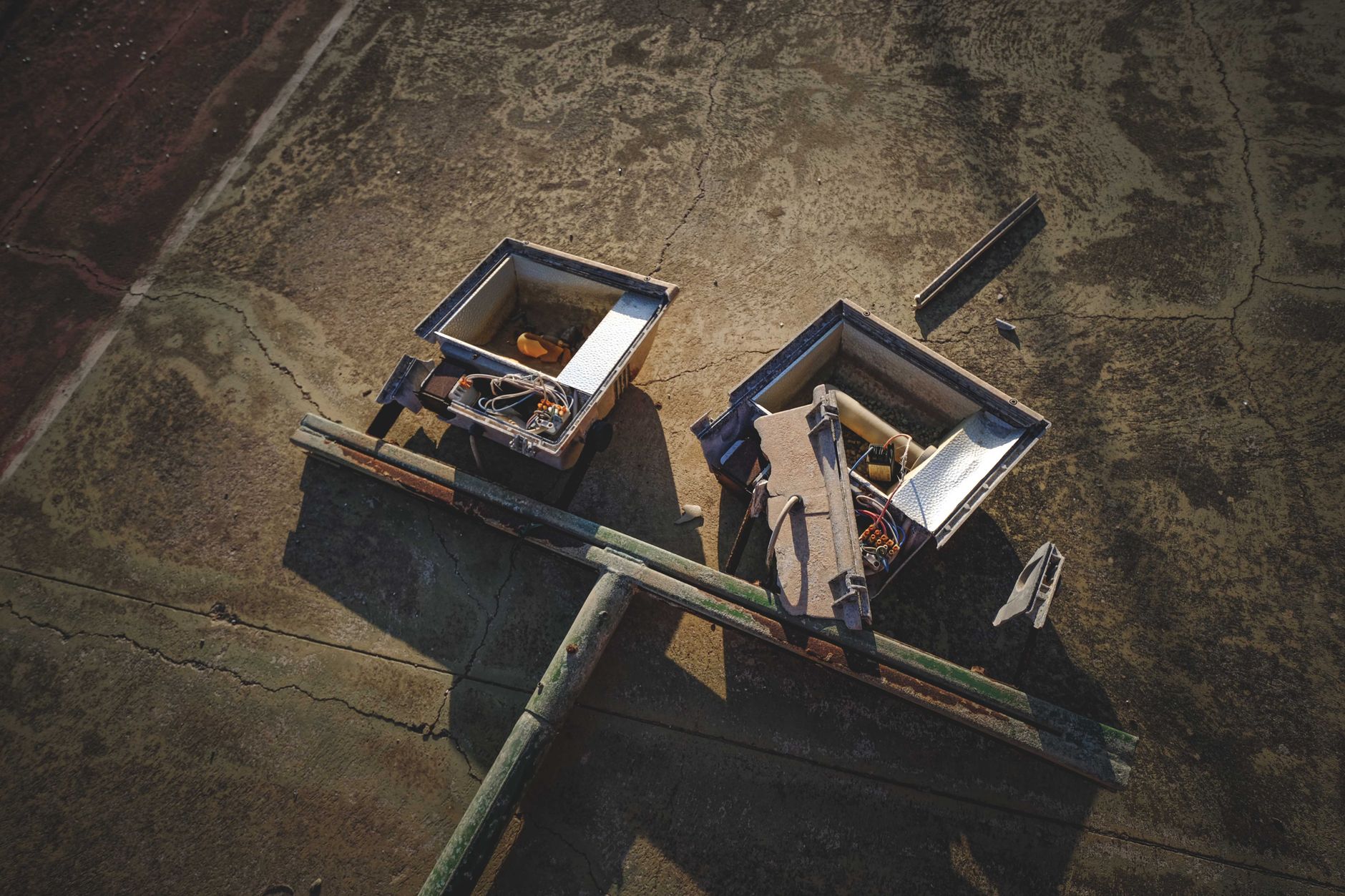 High angle view of discarded electronics with exposed wires and components on a cracked surface.